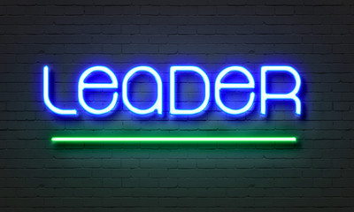 Leader neon sign on brick wall background.