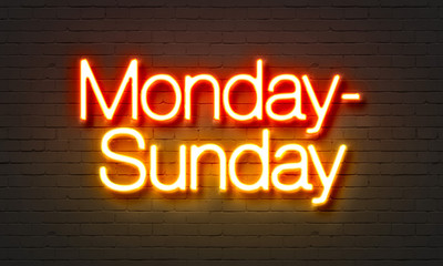 Monday-Sunday neon sign on brick wall background.