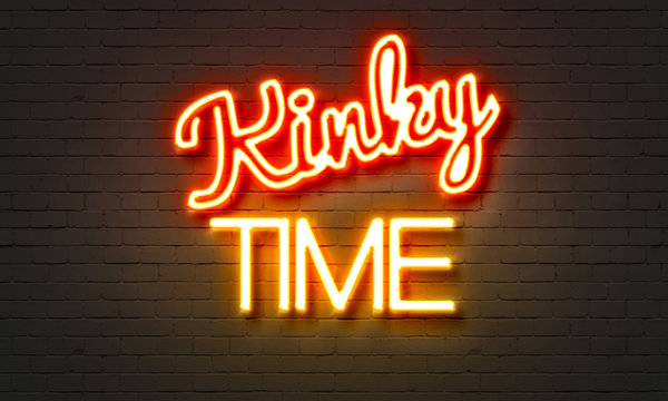 Kinky time neon sign on brick wall background.