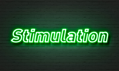 Stimulation neon sign on brick wall background.