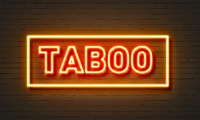 Taboo neon sign on brick wall background.