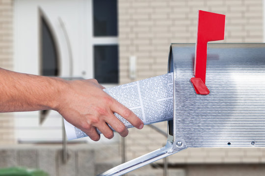 Man removing a newspaper from his mailbox