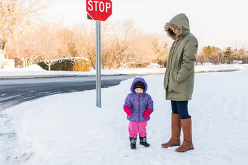 Mother and toddler wait for school bus in snow