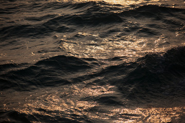 Rough sunset sea texture. Yellow waves with dark shadows close up. Powerful and peaceful nature concept.
