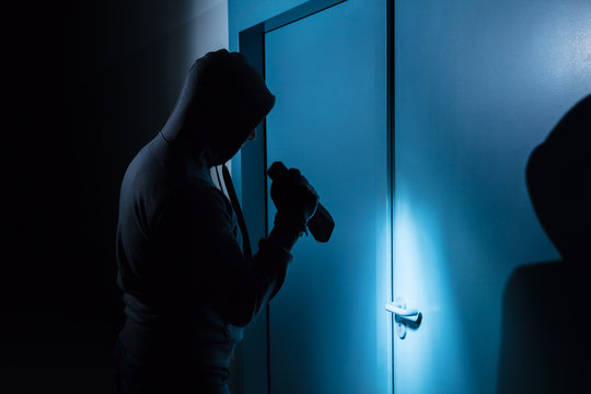 Burglar Holding Flashlight Outside The Door