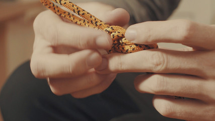Man's hands tying a mountaineering knot on a rope