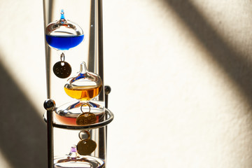 science glass tube with colorful chemical in glass ball  in front of white background with sunset light / galileo thermometer  
