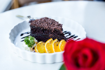 Soft focus delicious Chocolate cake decorated with orange on white dish. closeup.