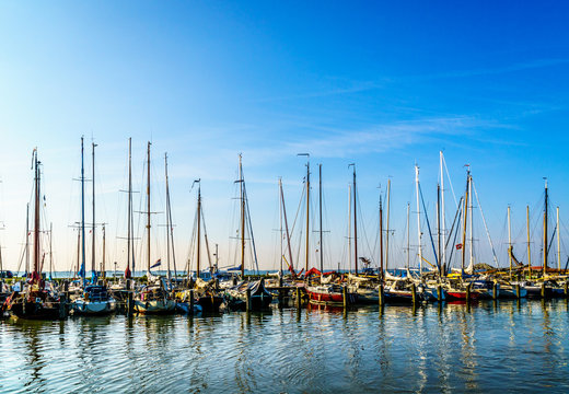 Sail boats moored in the small harbor of the historic fishing village of Marken in the Netherlands under clear skies