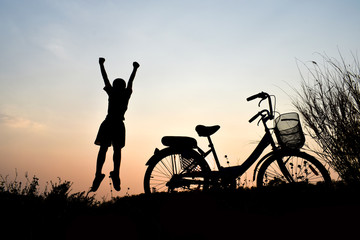 Silhouette boy and bicycle Background sunset
