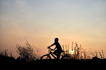 Fototapeta na wymiar Silhouette boy and bicycle Background sunset