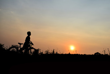 Silhouette boy and bicycle Background sunset