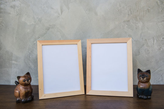 Two photo Frame and toy cat on a wooden on Gray wall background .