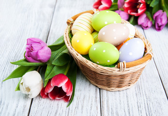 Obraz na płótnie Canvas basket with easter eggs and tulips