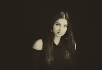 Fototapeta premium Young attractive woman with long black hair on black background.