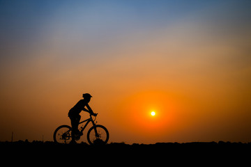 Obraz na płótnie Canvas Silhouette of young man cyclist on sunset.