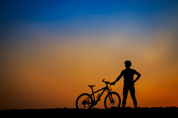 Silhouette of young man cyclist on sunset.