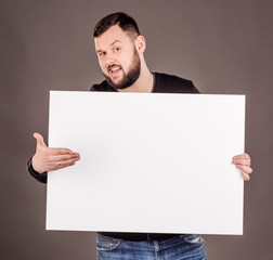 young man holding white blank panel with space for text on black background.