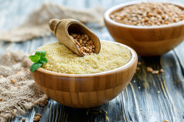 Bowl with raw couscous and scoop with wheat.