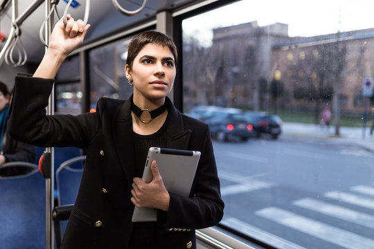 Young lady holding a tablet and riding a bus.