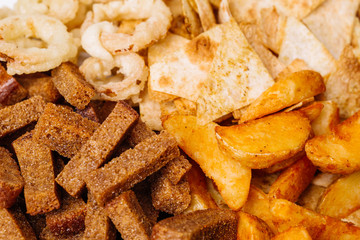 Fast food snacks composition with onion rings,  crackers, baked potatoes, chips, toast.