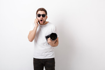 young professional photographer in white shirt holds digital cam