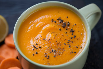 Close-up of a bowl with spicy carrot cream-soup, selective focus
