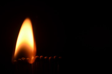 Line of lighted matches on black background