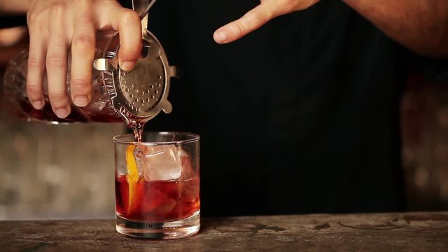 Bartender pouring cocktail into glass