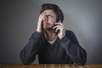 Depressed man hearing bad news over his cell phone