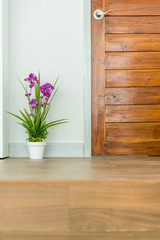 artificial plant with purple flower near the door  wooden and floor