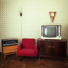 Vintage room with wallpaper, tv, old fashioned armchair, retro player, loudspeakers, clocks and...