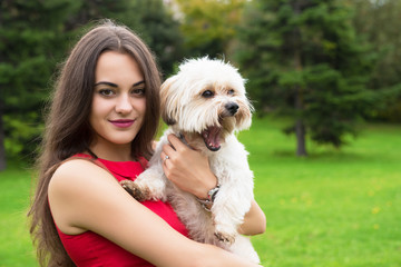 Girl with puppy. Portrait of attractive happy smiling young woman holding cute little dog, summer park outdoor.