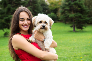 Girl with puppy. Portrait of attractive happy smiling young woman holding cute little dog, summer park outdoor.