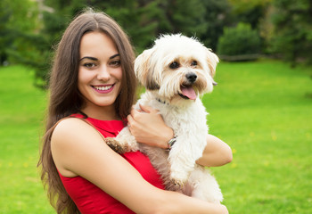 Girl with puppy. Portrait of attractive happy smiling young woman holding cute little dog, summer park outdoor.