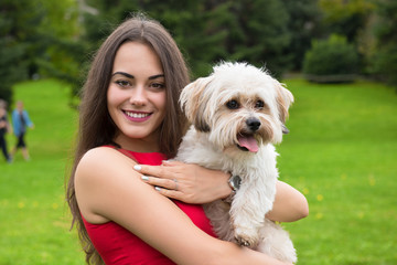 Girl with puppy. Portrait of attractive happy smiling young woman holding cute little dog, summer park outdoor.