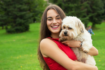 Girl with puppy. Portrait of attractive happy smiling young woman holding cute little dog, summer park outdoor.