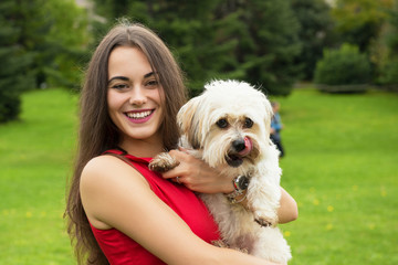 Girl with puppy. Portrait of attractive happy smiling young woman holding cute little dog, summer park outdoor.