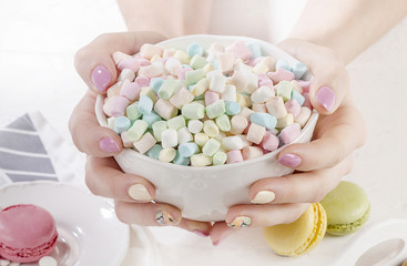 Womans hands with marshmallows.