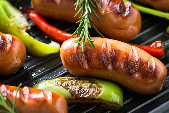 Fried sausages with  vegetables in grill pan at black background