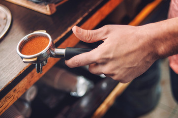 Closeup of hand with the baristas Holder with freshly ground coffee.