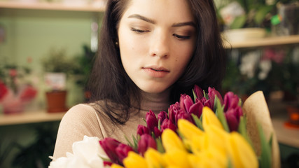 Fototapeta premium Portrait of pretty women in flowers shop holding bouquet of tulips