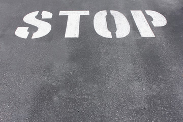 Word stop written on asphalt road