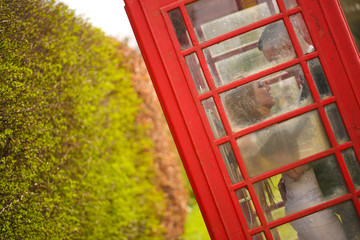 Groom and bride near a phone cabin in London