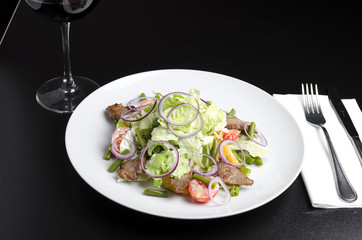 Salad with beef roast beef and vegetables on a black background