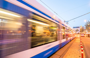Fototapeta na wymiar Amsterdam. Tram speeding at sunset in city streets