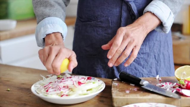 Woman squeezing lemon over cut-up radishes and fennel
