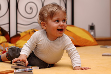 Toddler playing with small books on the bed