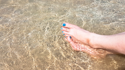 Woman's leg lay on the white armchair on the beach