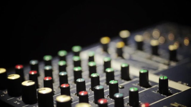 Vertical dolly shot video of a mixer desk with many buttons.